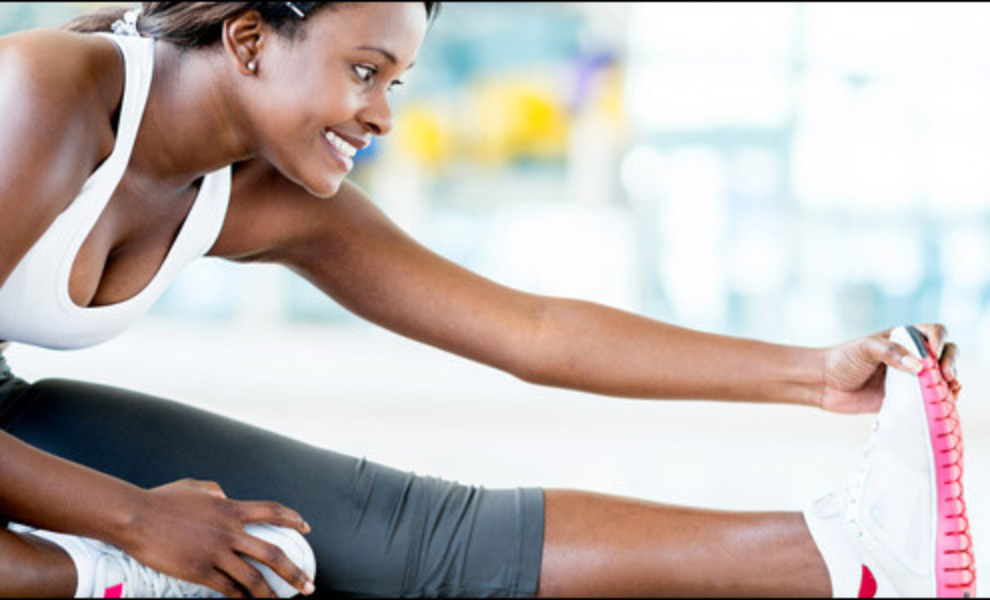 Woman stretching her legs in a gym, with a blurred background