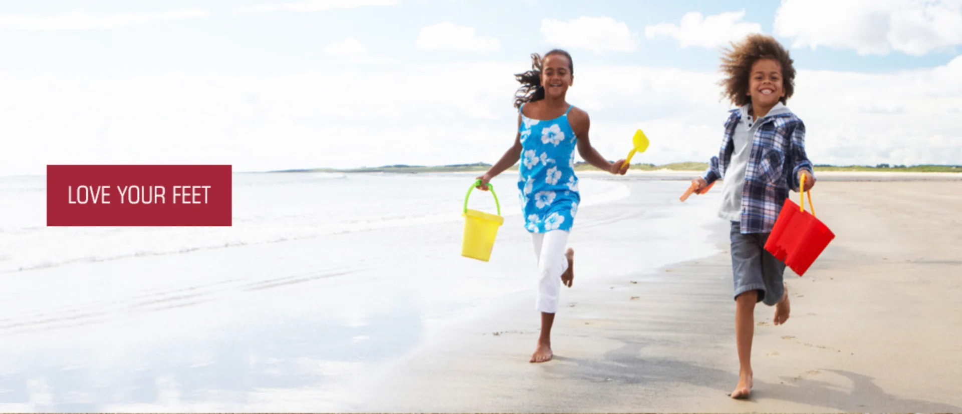 Two children running on the beach with buckets and spades in their hands