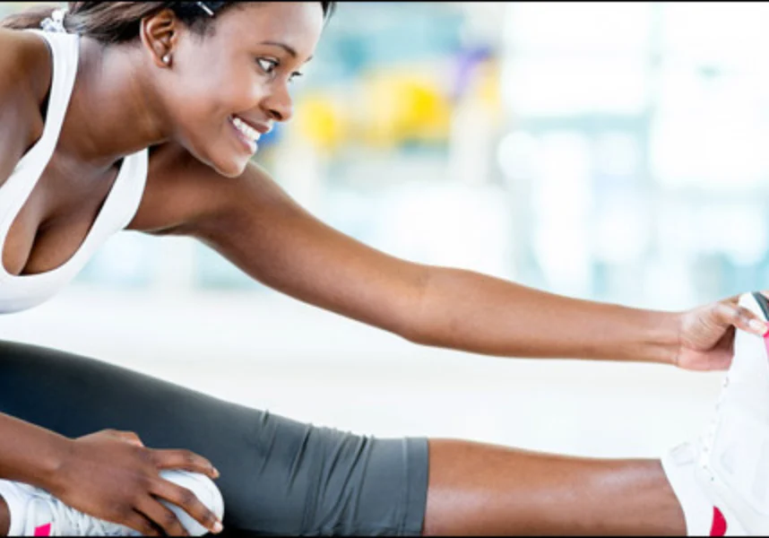 Woman stretching her legs in a gym, with a blurred background